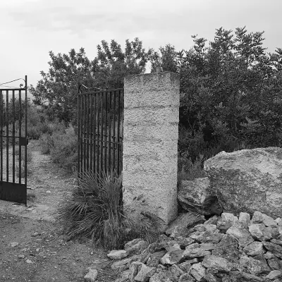 Portón de hierro con pilar de piedra en campo