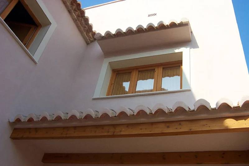 Casa bioclimática en Benimàmet: Diseño sostenible y eficiente Casa bioclimática en Benimàmet diseñada por Conesa & Franch Arquitectos, con un techo de madera, una ventana con contraventanas y un diseño sostenible