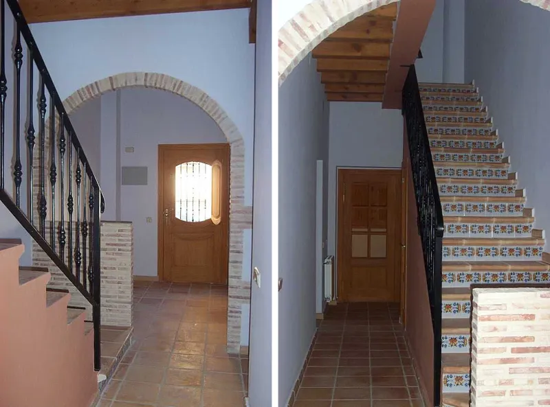 Diseño interior de un pasillo con escalera y puerta de madera Diseño interior de un pasillo con escalera con barandilla de forja negra y puerta de madera