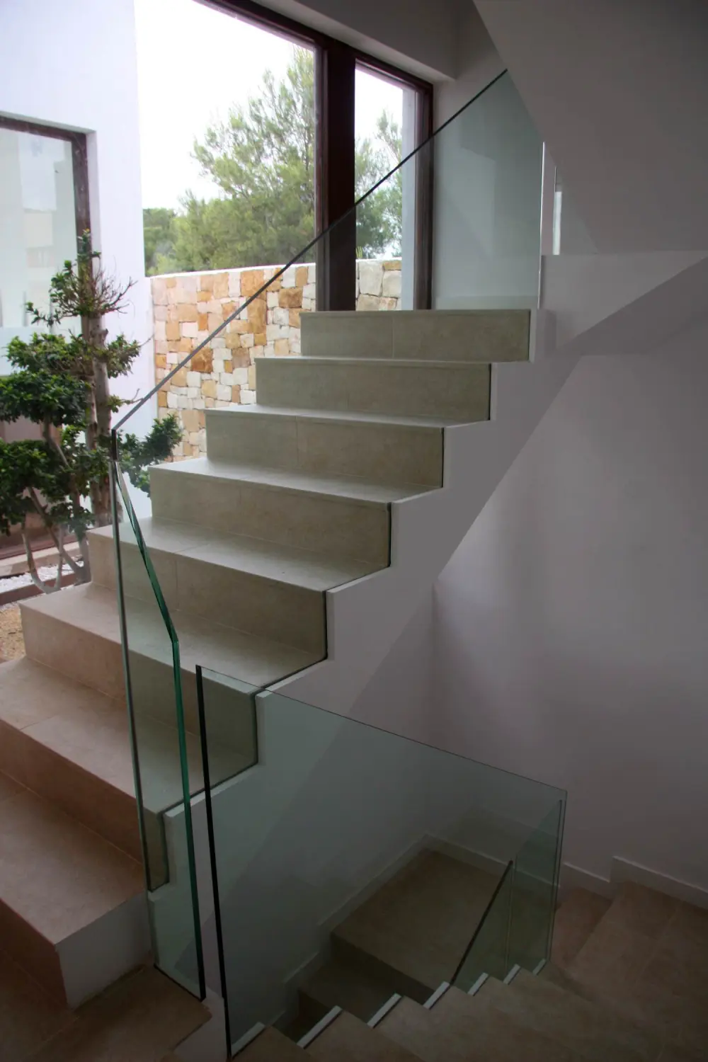 Escaleras blancas con barandilla de cristal en el interior de casa Bétera