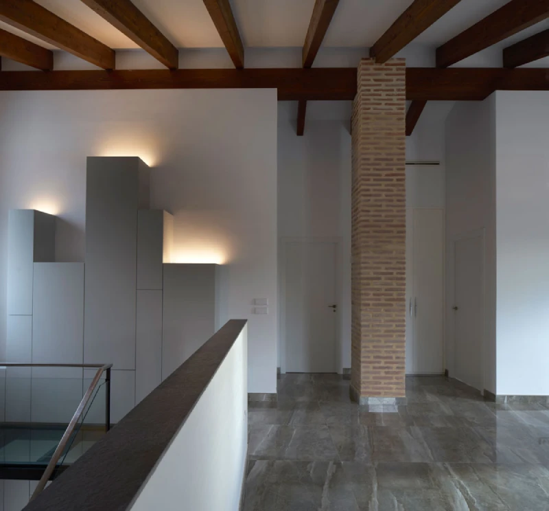 Interior minimalista con vigas de una vivienda con columna de ladrillo y techo con vigas de madera